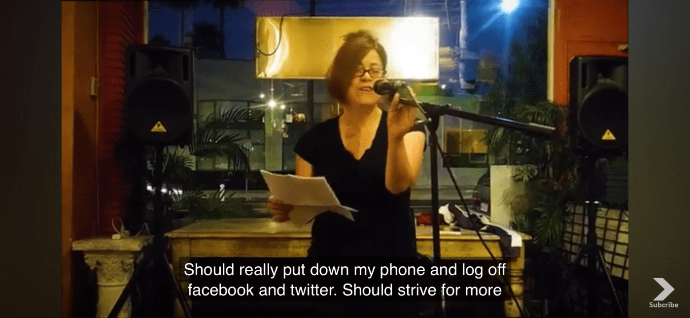 Screenshot of me at a coffee shop reciting a poem in front of a microphone. Caption reads should really put down my phone and log off facebook and twitter. Should strive for more